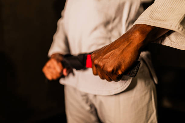 Mãos ajustando a faixa preta sobre o kimono branco